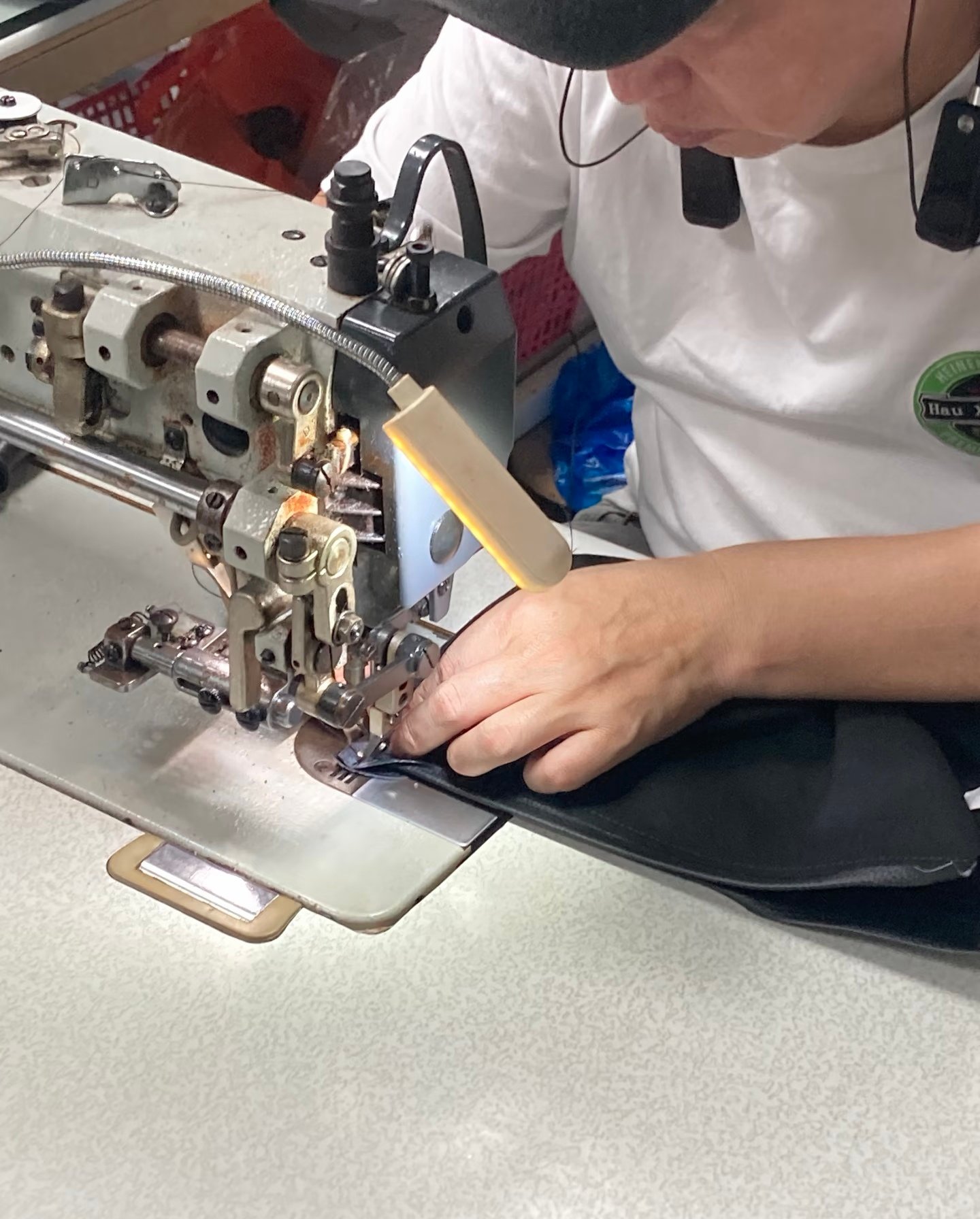 Worker sewing black bag material on an industrial sewing machine