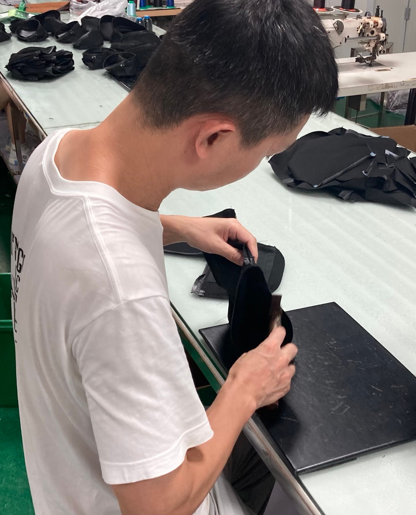 Worker assembling black bag components at a factory worktable