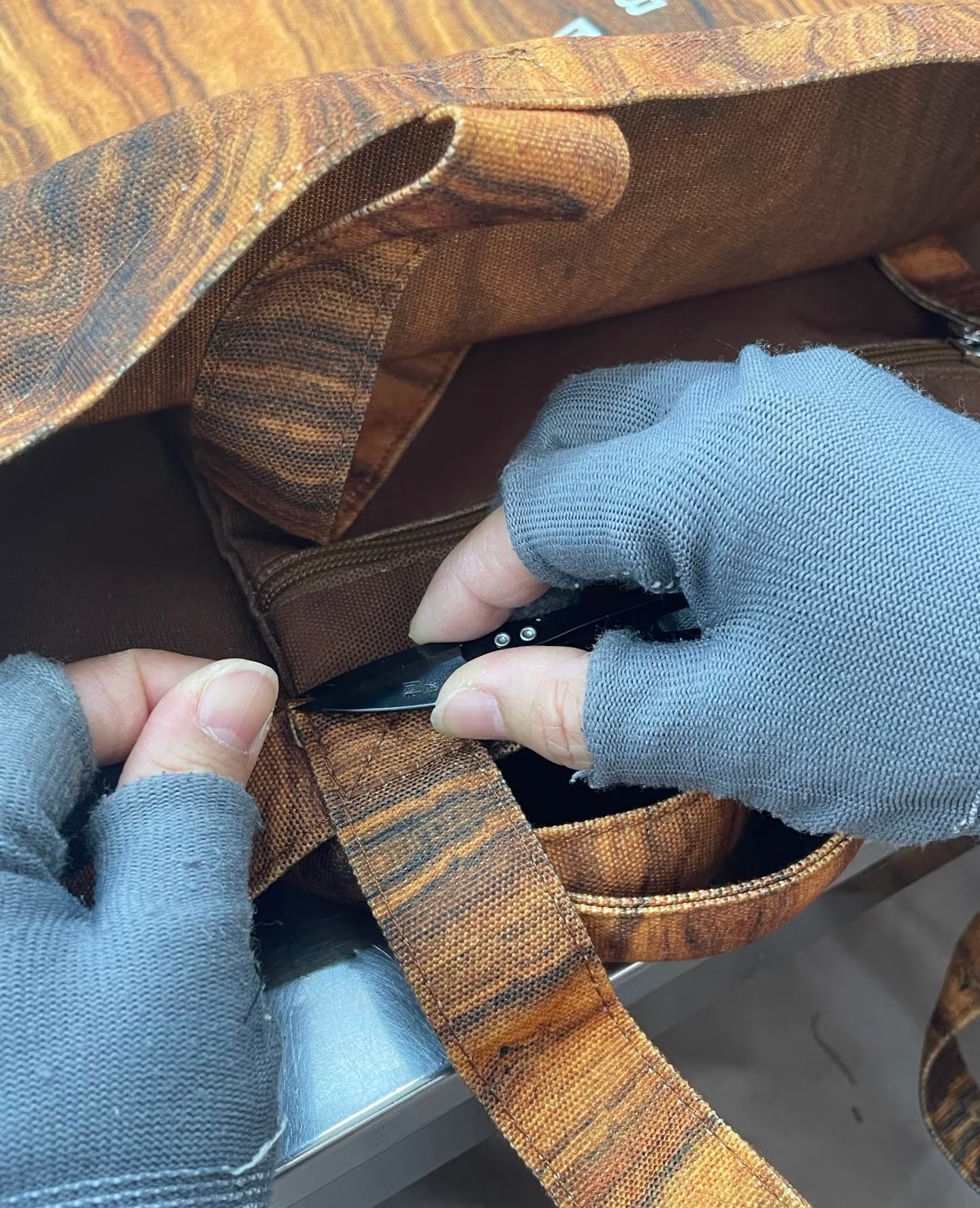 Inspector trimming loose threads during backpack quality control