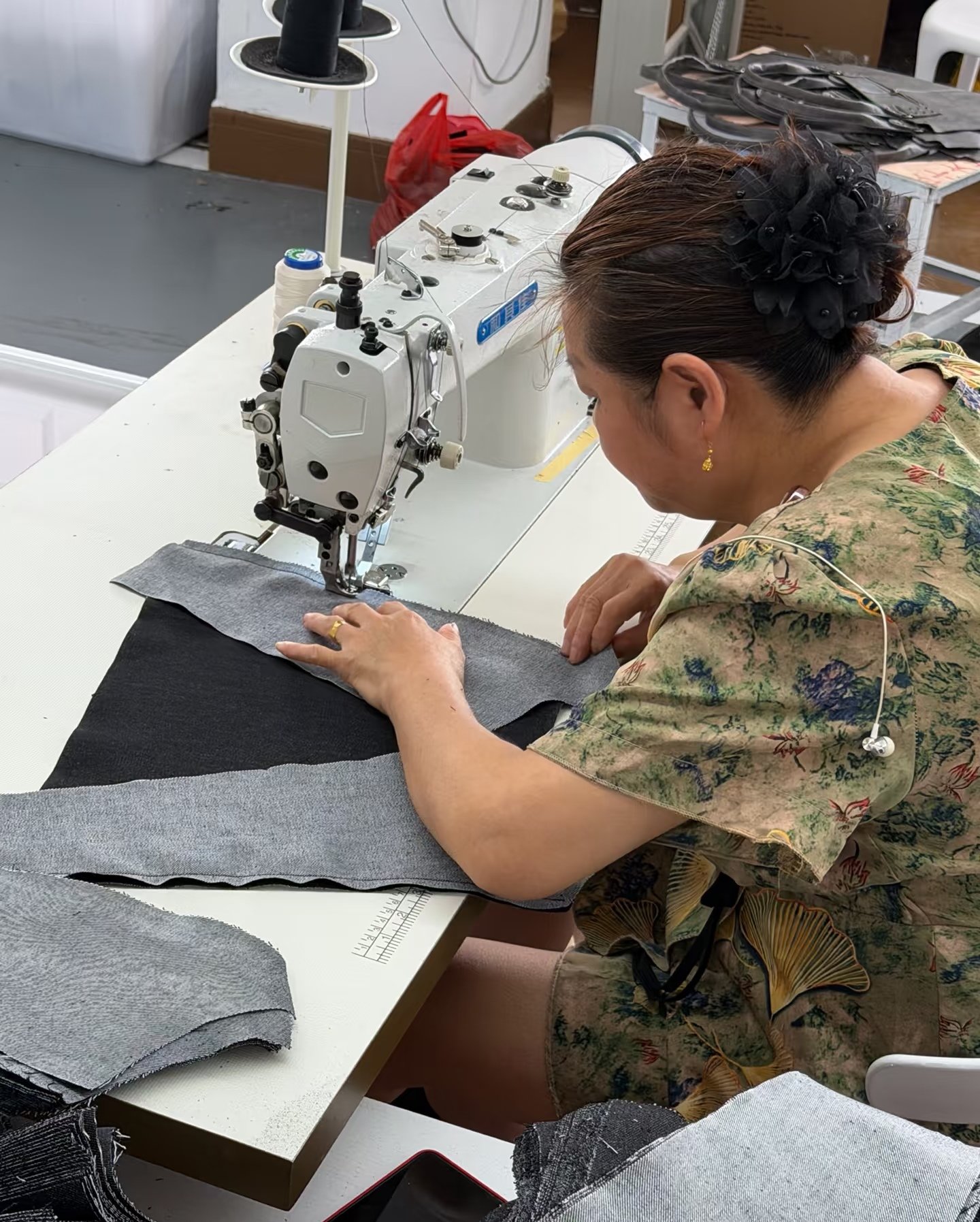 Worker sewing backpack fabric panels during assembly
