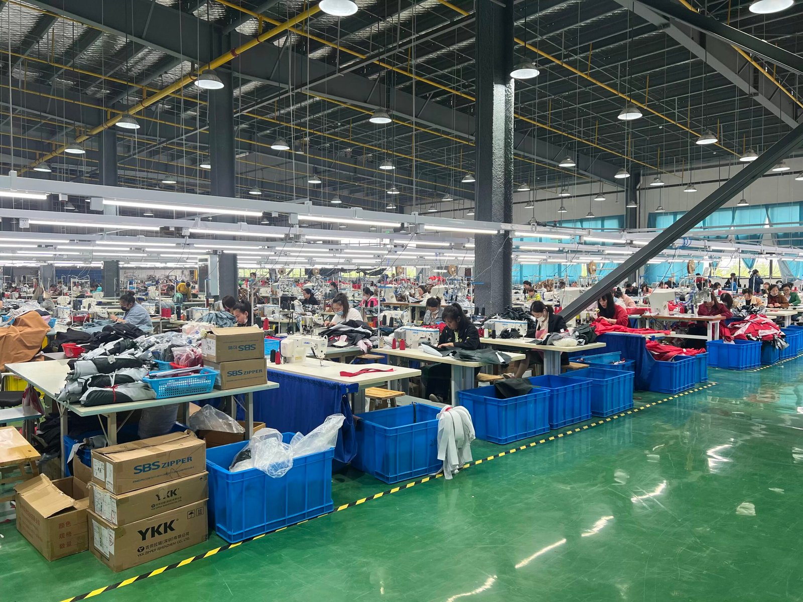 Backpack production workshop with workers operating industrial sewing machines